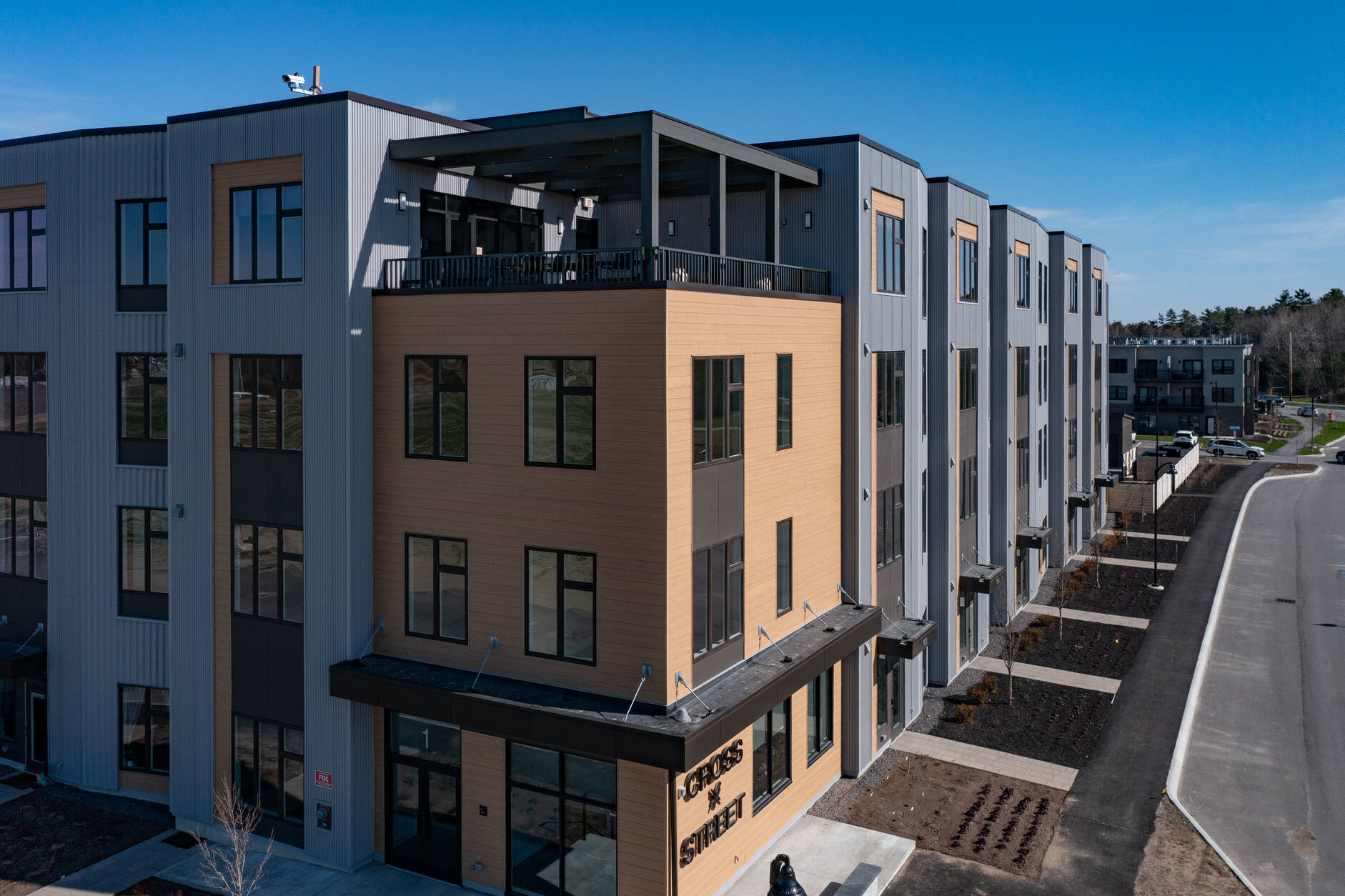 Aerial view of Cross Street Condos in Scarborough, Maine, showing modern multi-story condominium buildings with wood-look siding, private entrances, and landscaped walkways.