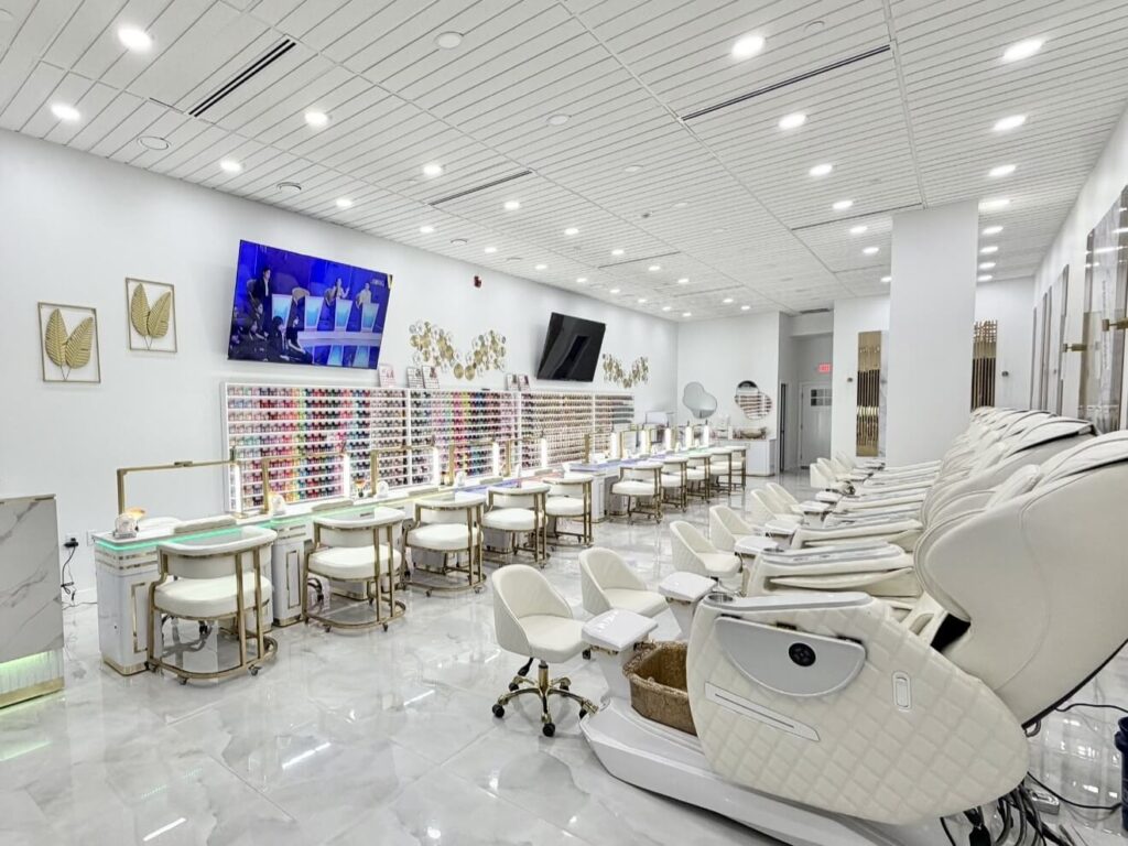 Modern nail salon in Scarborough, ME with rows of manicure stations, pedicure chairs, and colorful nail polish displays.